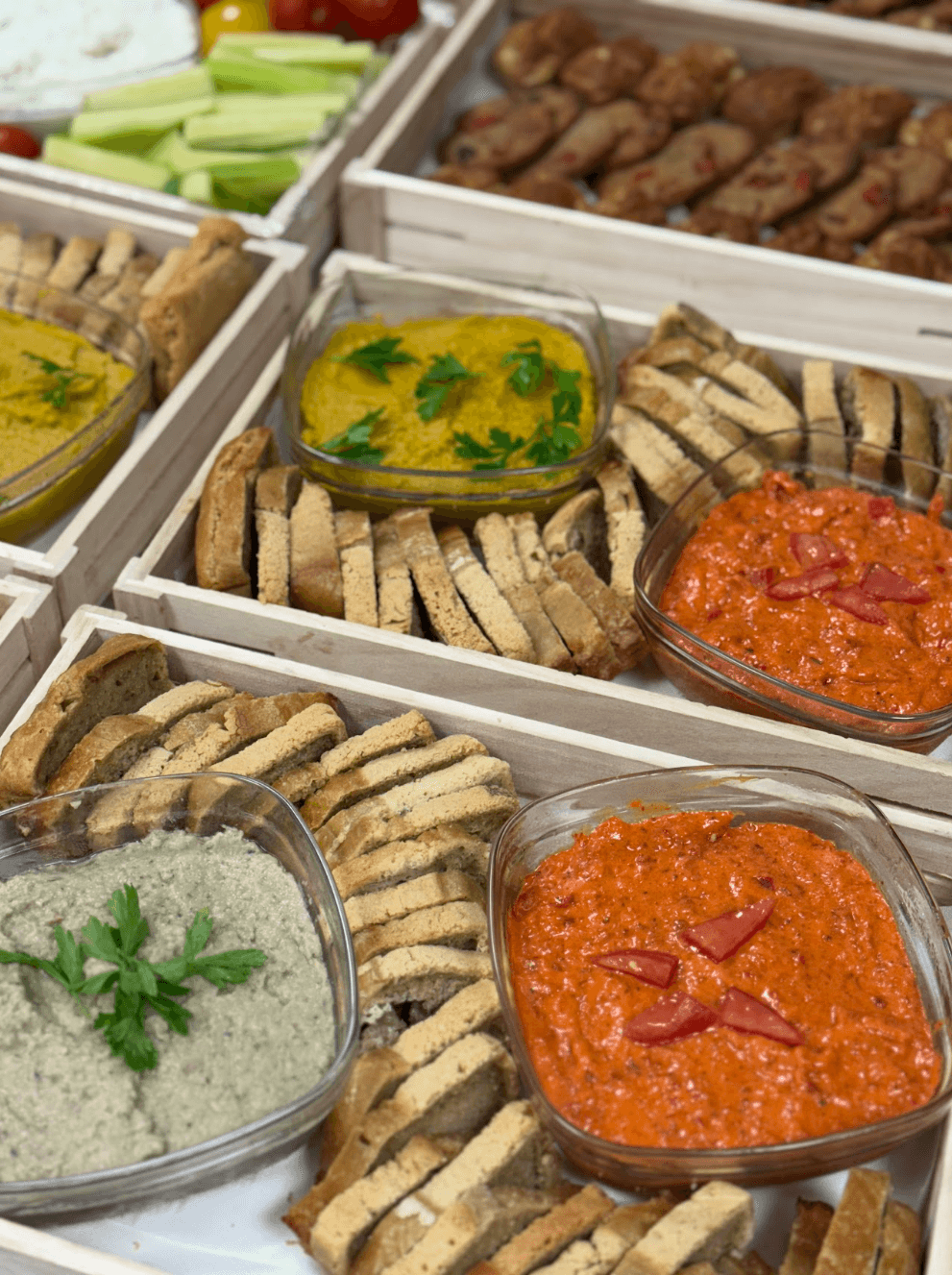 Plateaux en bois garnis de diverses trempettes colorées, de pain tranché et de légumes frais.