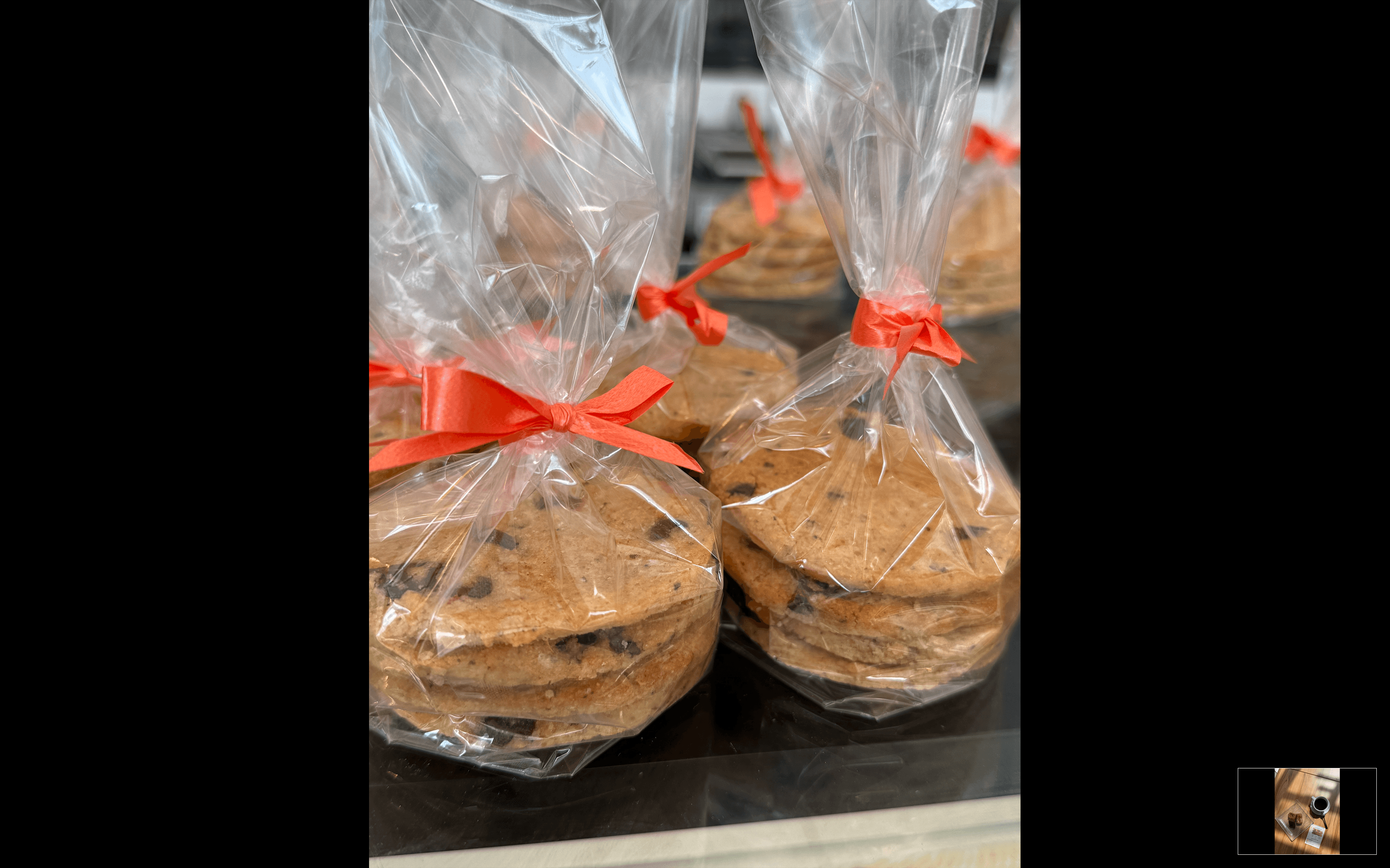 Piles de cookies aux pépites de chocolat emballées dans des sachets transparents avec rubans orange.